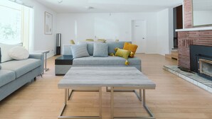 A modern living room with a grey sofa, a coffee table, and a fireplace. - Waterfront Inn (Penticton)