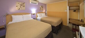 A hotel room with two beds, a desk, and a chair.