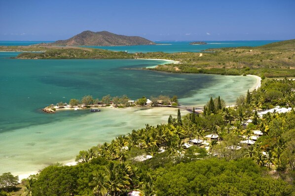 A coastal resort with clear turquoise waters, a beach, and lush greenery. - Malabou Beach Hotel (Poum)