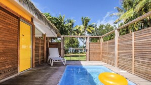 Eine Holzterrasse mit Pool, einer gelben Tür und einem weißen Liegestuhl.