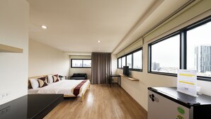 A hotel room with a bed, a desk, a TV, and a window with a city view. - L.A.Tower Hotel (Bangkok)
