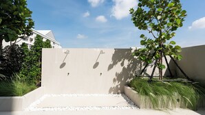 A modern outdoor area with a concrete wall, a small pool, and a tree. - L.A.Tower Hotel (Bangkok)