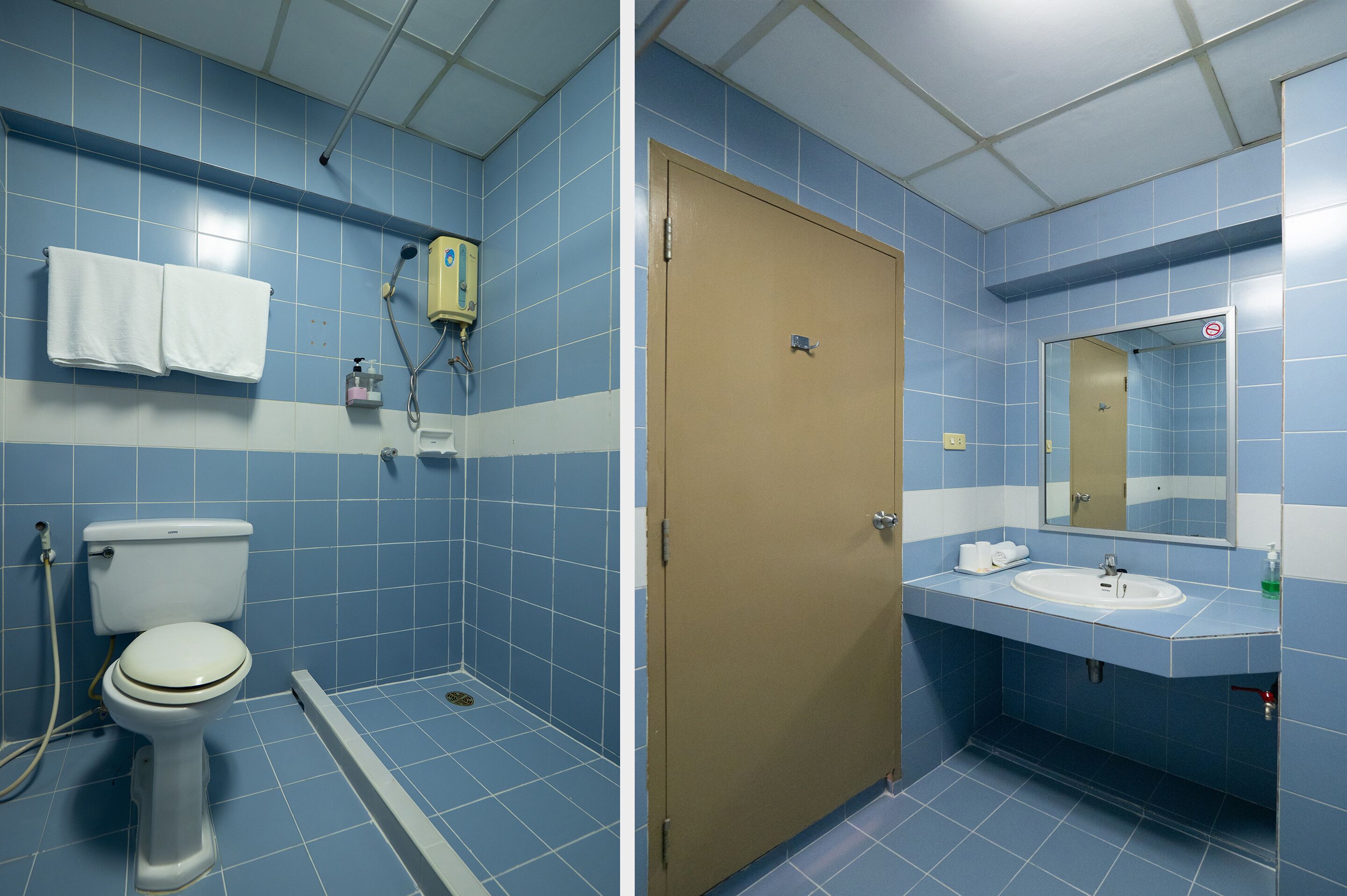 A bathroom with blue tiles, a toilet, a shower, and a sink.