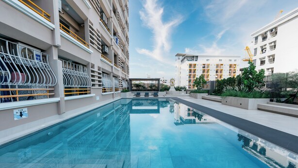 A swimming pool with a clear view of the surrounding buildings and a clear sky. - L.A.Tower Hotel (Bangkok)