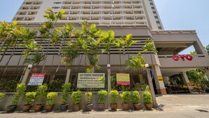 A multi-story hotel with balconies, palm trees, and signs in a foreign language. - L.A.Tower Hotel (Bangkok)