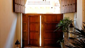 A hallway with a chandelier, wooden doors, a rug, and potted plants. - Hotel Casa Don Sancho by Mustique (Cartagena)