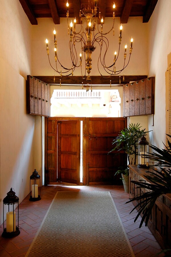 A hallway with a chandelier, wooden doors, a rug, and potted plants. - Hotel Casa Don Sancho by Mustique (Cartagena)