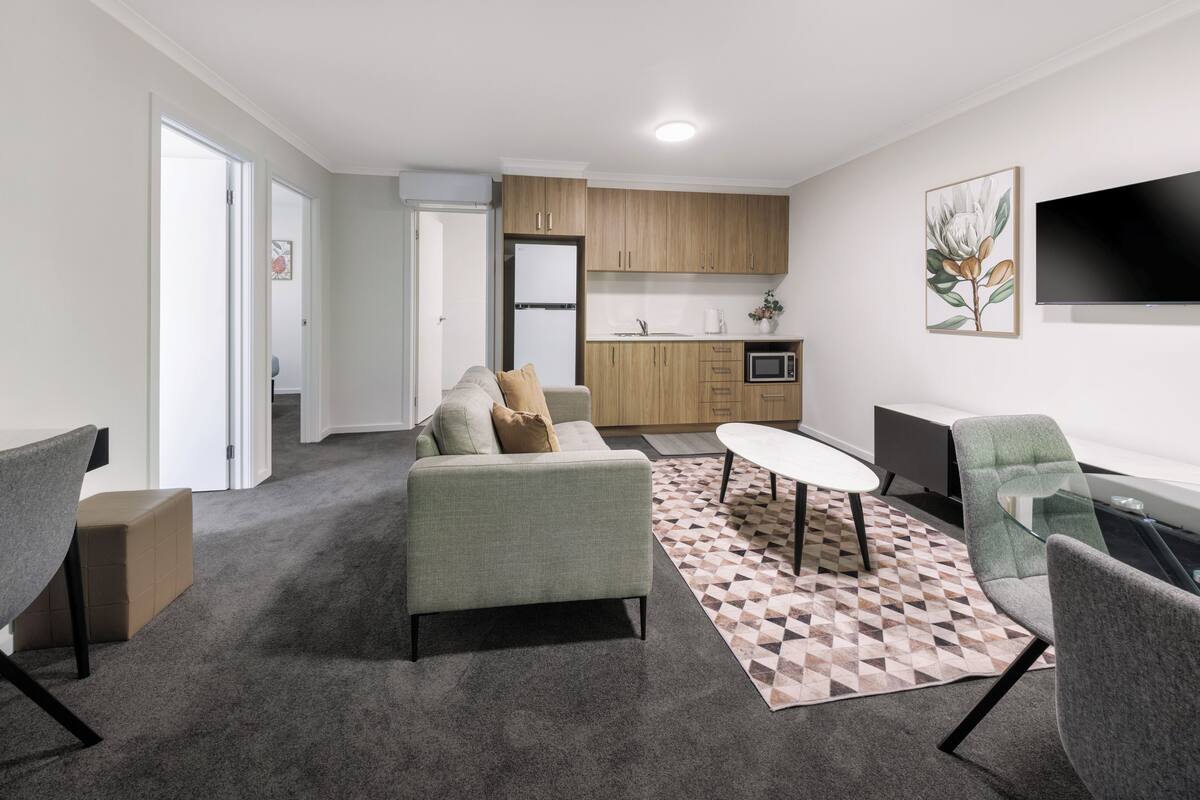 A modern living room with a sofa, a coffee table, and a TV.