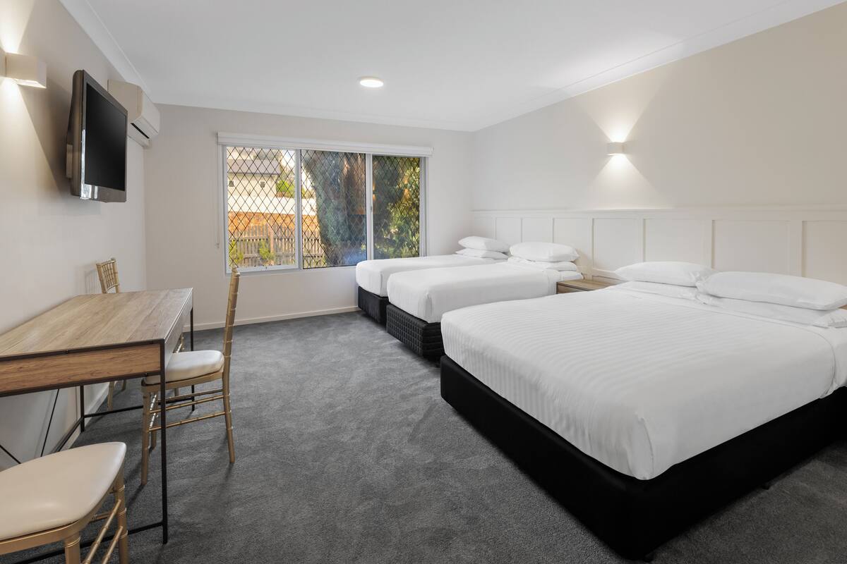 A hotel room with a bed, a desk, and a TV.