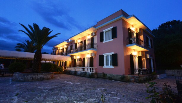A two-story building with balconies, a stone courtyard, and a palm tree. - Argo Hotel (Corfu)
