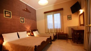 A hotel room with two single beds, a desk with a chair, a television mounted on the wall, and a window with curtains. - Argo Hotel (Corfu)