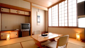 A traditional Japanese room with tatami flooring, a low table, a television, and a sliding door. - Hotel Pony Onsen (Towada)