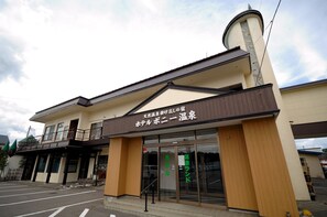 A hotel with a sign in Japanese, a balcony, and a parking lot in the background. - Hotel Pony Onsen (Towada)