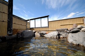 A traditional Japanese onsen with a wooden bathhouse, a small stream, and rocks. - Hotel Pony Onsen (Towada)