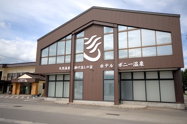 A modern building with large windows and a prominent logo. - Hotel Pony Onsen (Towada)