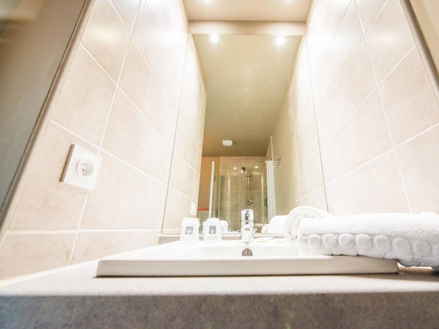 A bathroom with a sink, mirror, and towels.