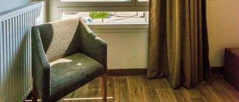 Una habitación con un ventanal grande, una silla, una cama y un radiador.