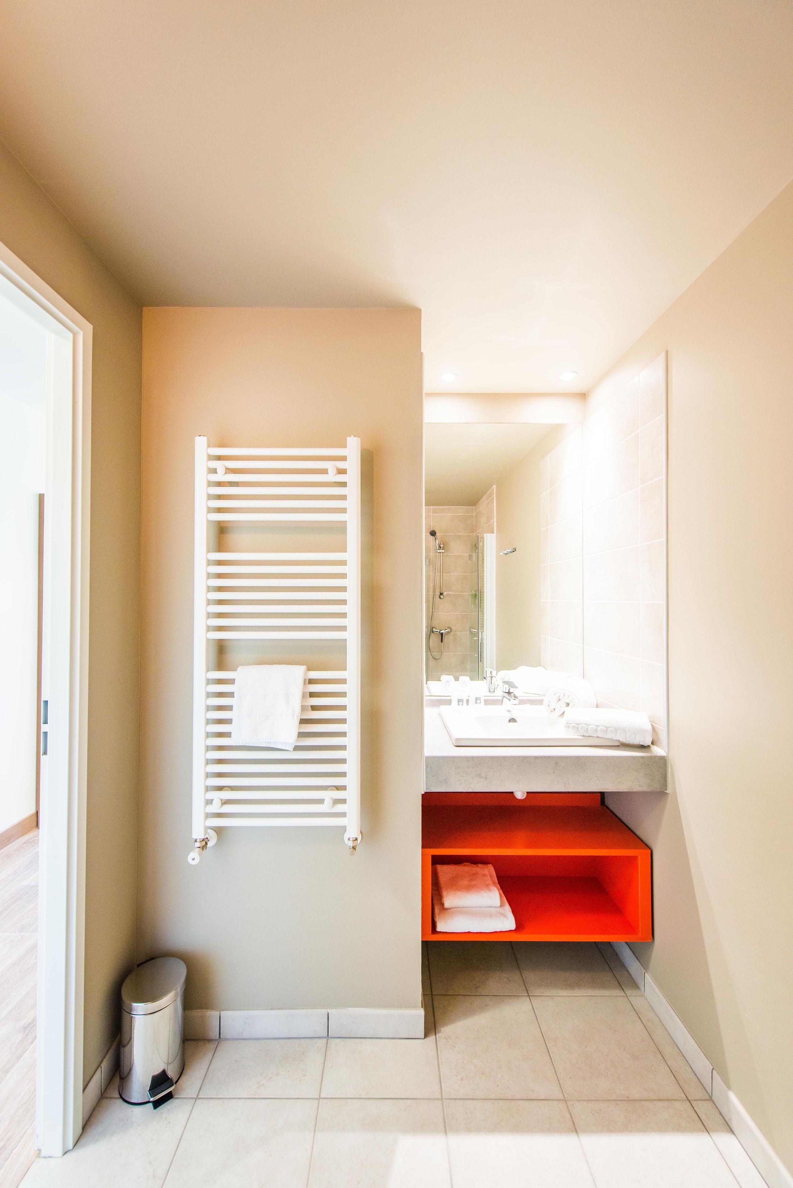 Une salle de bain moderne équipée d’un porte-serviettes, d’un lavabo et d’un espace douche.