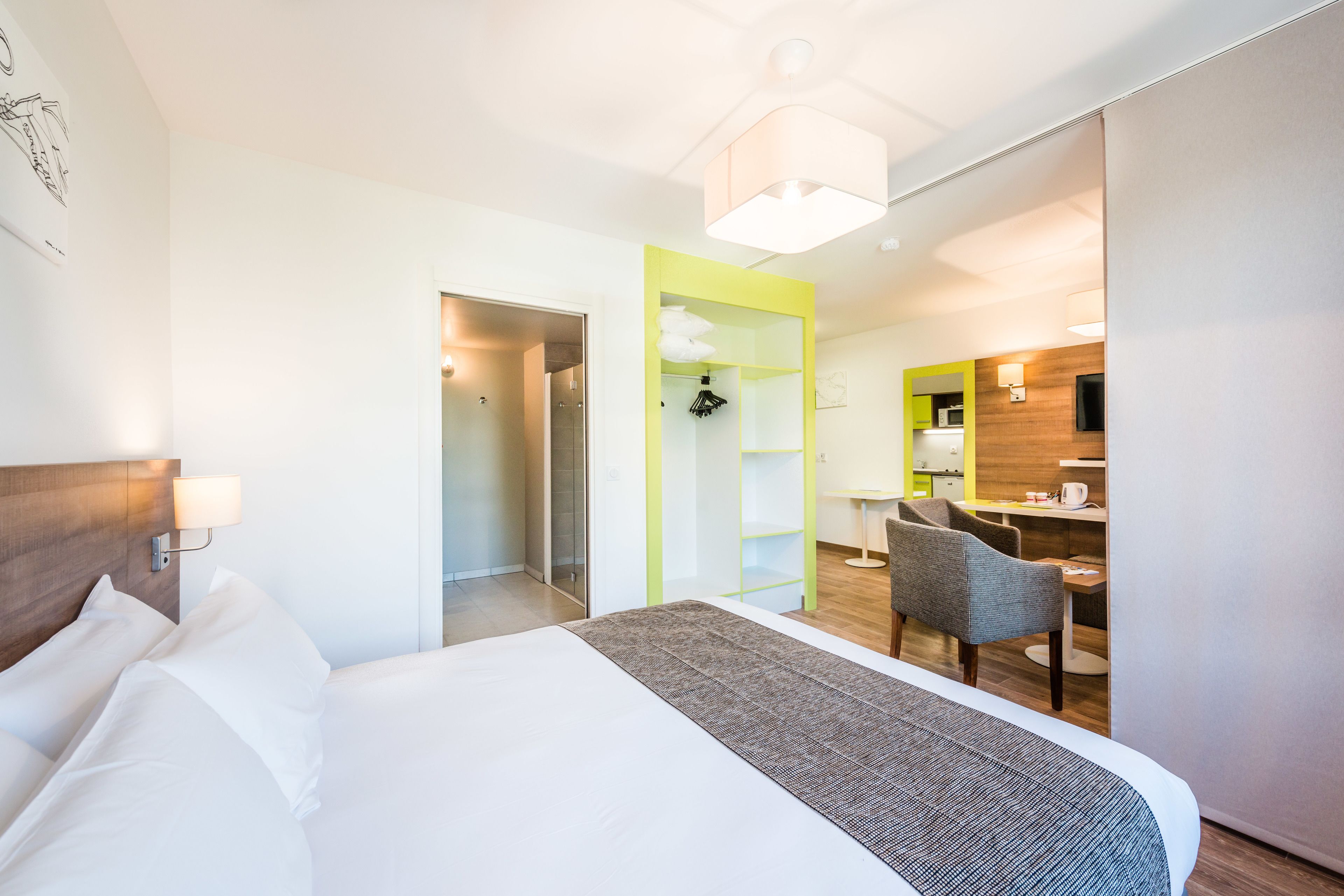 Una habitación de hotel con cama, escritorio, silla, armario y baño.