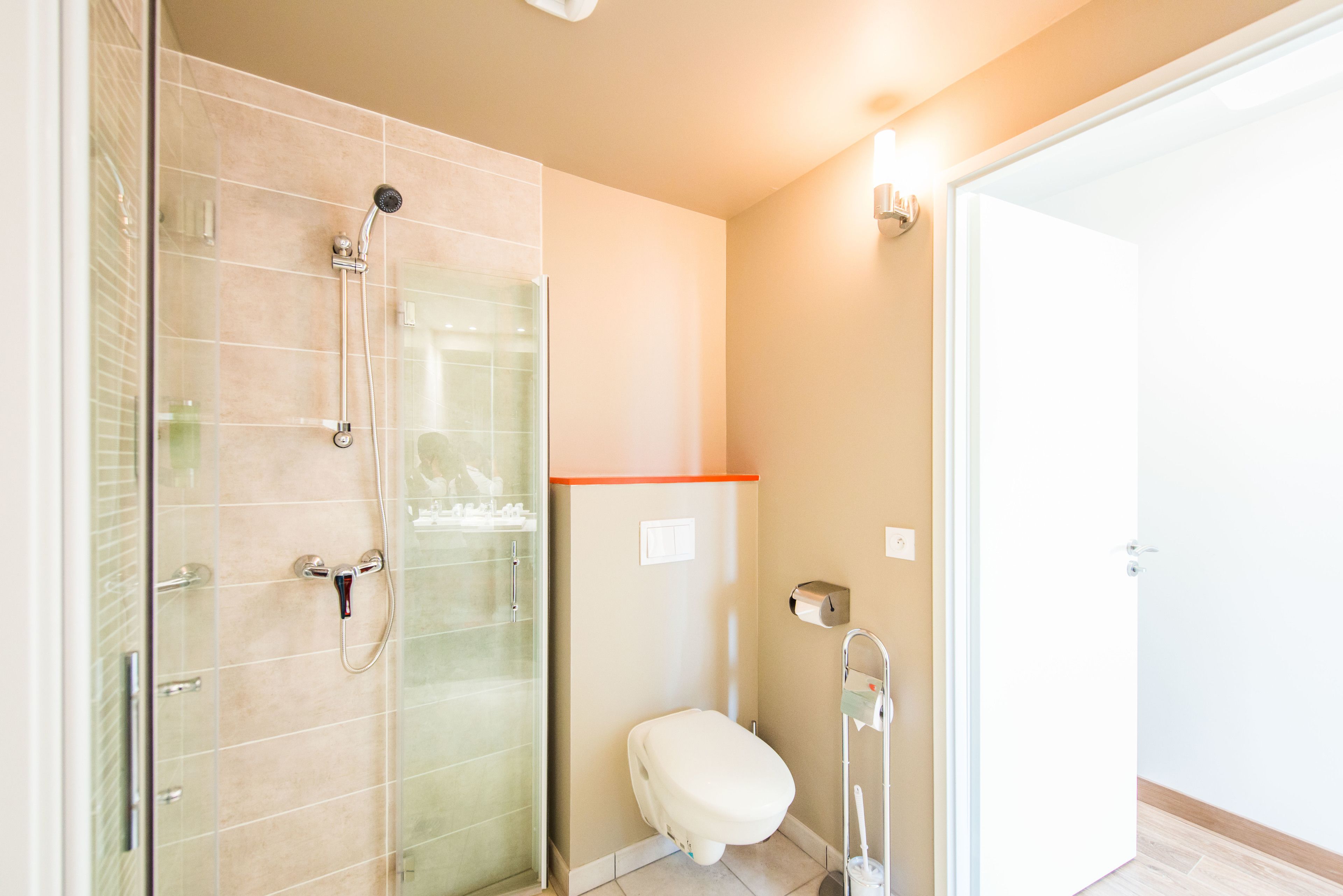 A modern bathroom with a glass-enclosed shower, a toilet, and a sink.
