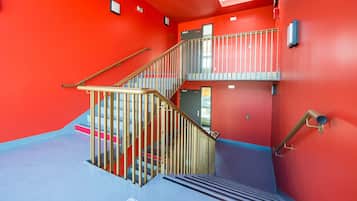 Una escalera con barandillas metálicas y piso azul, que conduce a un segundo nivel.