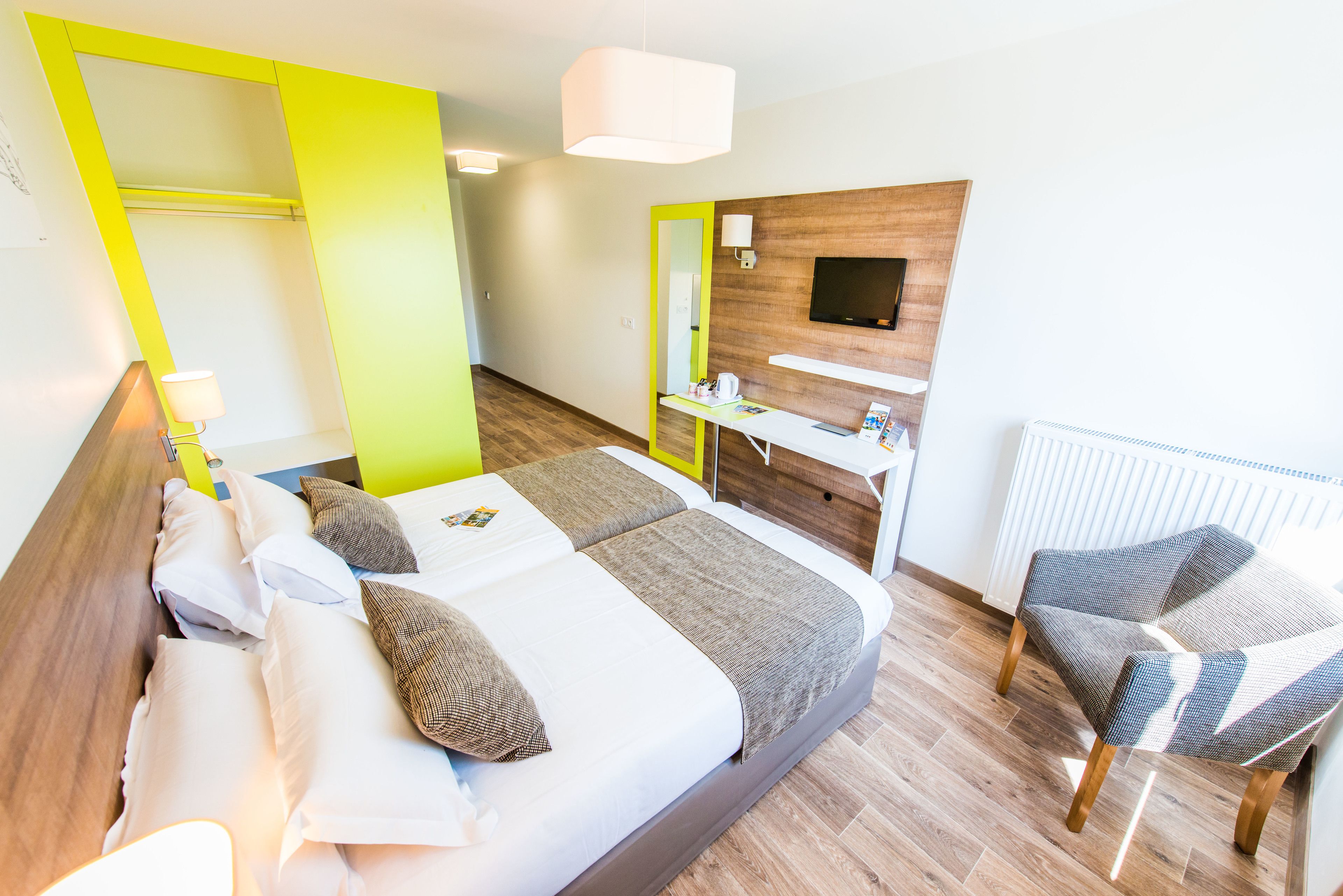 Une chambre d’hôtel moderne équipée d’un lit, d’un bureau, d’une chaise et d’un téléviseur.