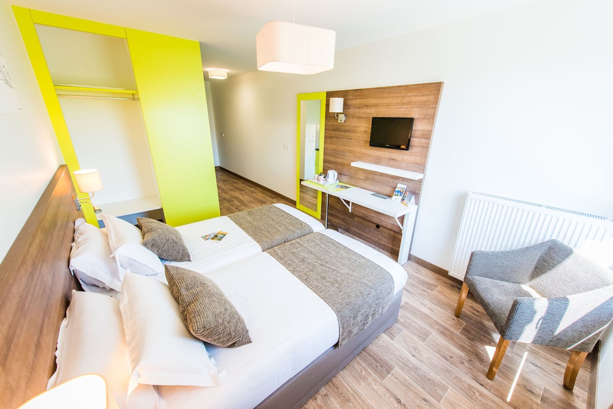 Une chambre d’hôtel moderne équipée d’un lit, d’un bureau, d’une chaise et d’un téléviseur.