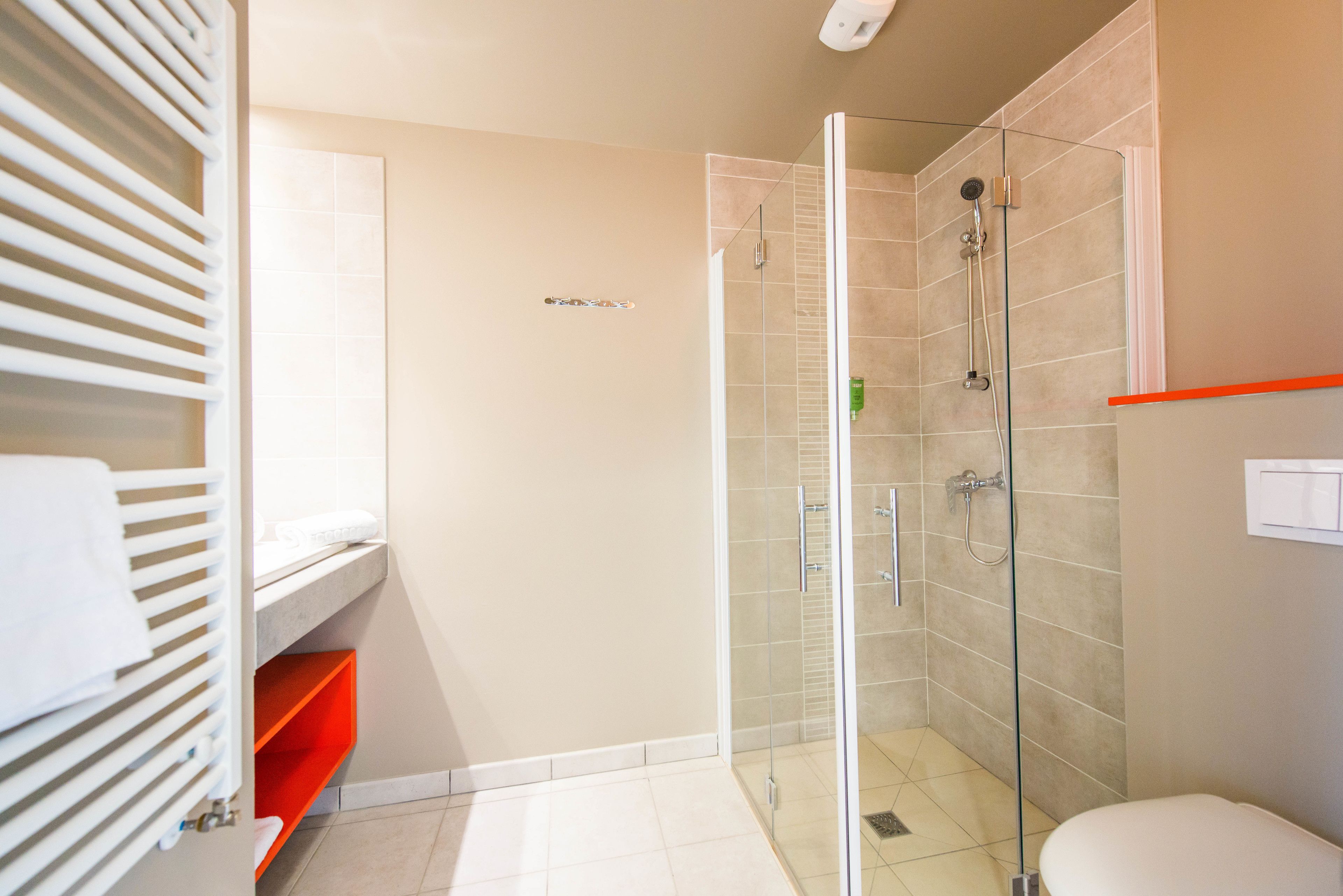 A modern bathroom with a glass shower enclosure, a toilet, and a sink with a towel rack.