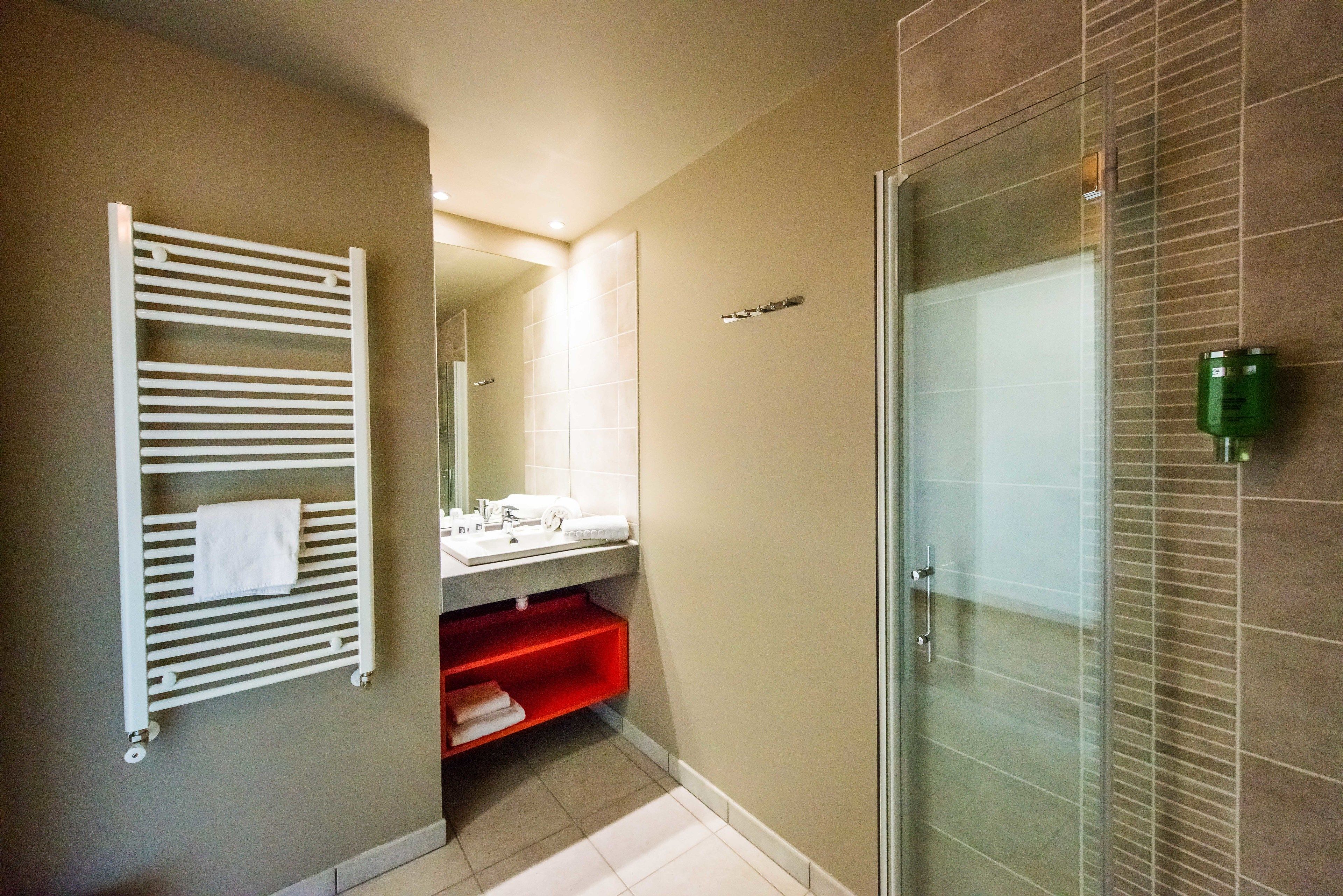 Een moderne badkamer met een douchecabine van glas, een witte handdoekhouder en een rode plank.