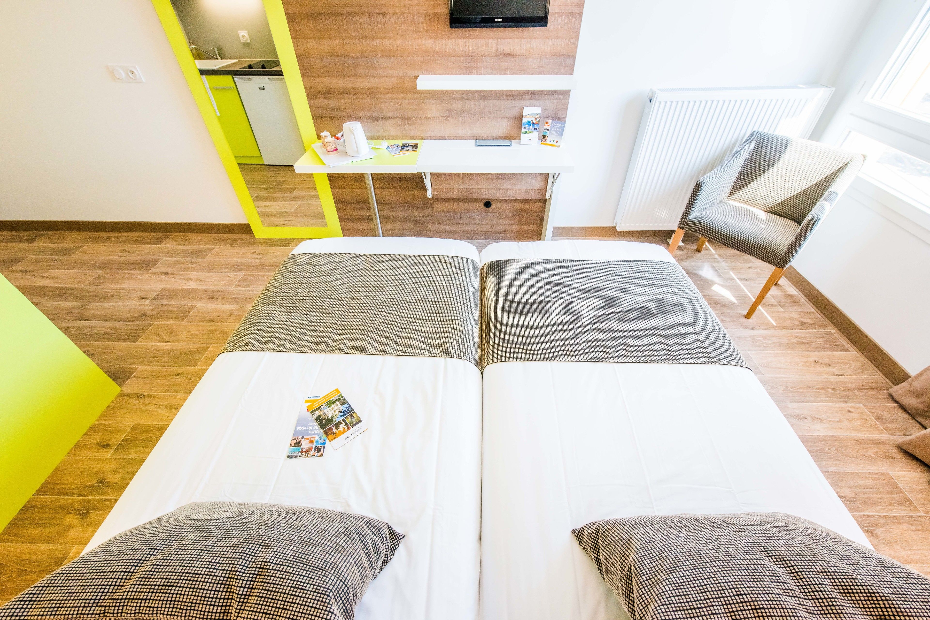 A hotel room with two beds, a small desk, a chair, and a TV.