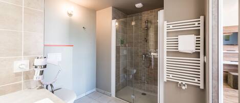 A modern bathroom with a glass-enclosed shower, a white sink, and a towel rack.