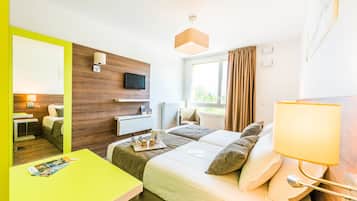 Una habitación de hotel con cama, mesita de noche, lámpara y televisión en la pared.
