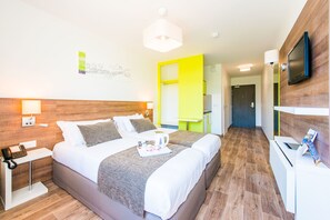 A modern hotel room with a large bed, bedside tables, a desk, and a TV mounted on the wall.