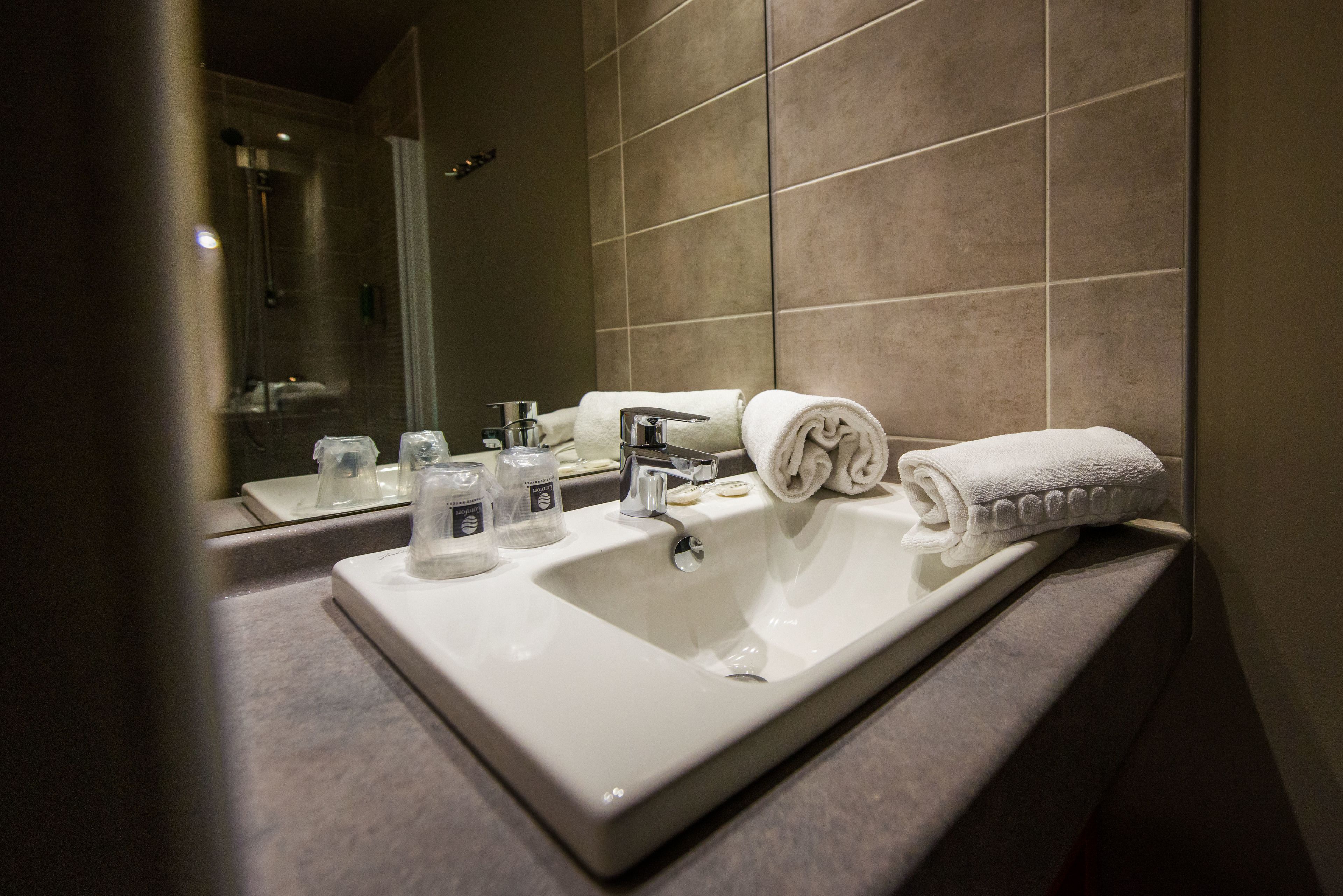 A bathroom with a large sink, mirror, and two towels.