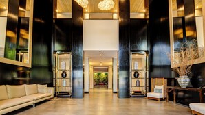 Un hall amplio con diseño moderno, que cuenta con un espacio central abierto, un mostrador de recepción y una zona de estar con sofás.