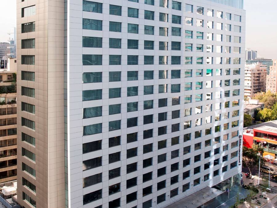 A modern high-rise hotel with a grid of windows, a flat roof, and a landscaped courtyard.