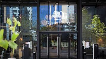 The entrance to a DoubleTree by Hilton hotel with glass doors, a signboard, and a potted plant in the foreground.