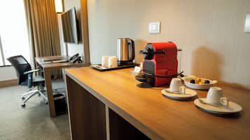 Habitación de hotel con un escritorio de madera, una cafetera roja, un hervidor y un cuenco con cubitos de azúcar.
