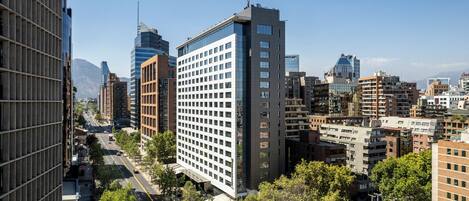 Un hotel moderno de gran altura, con un llamativo frente de vidrio y una entrada central.