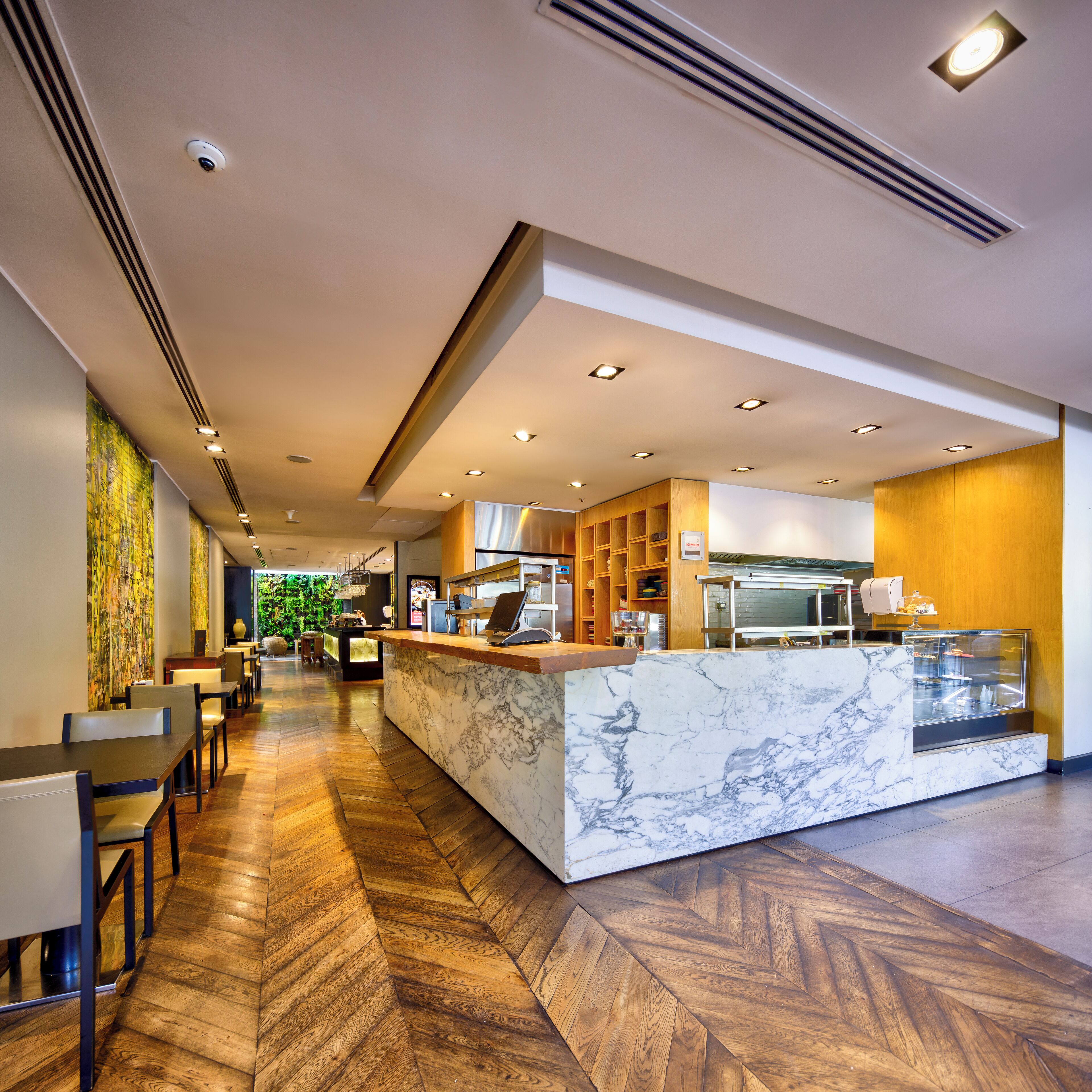 Un hall d’hôtel moderne avec un comptoir d’accueil en marbre, un plancher en bois et une vue sur l’extérieur.
