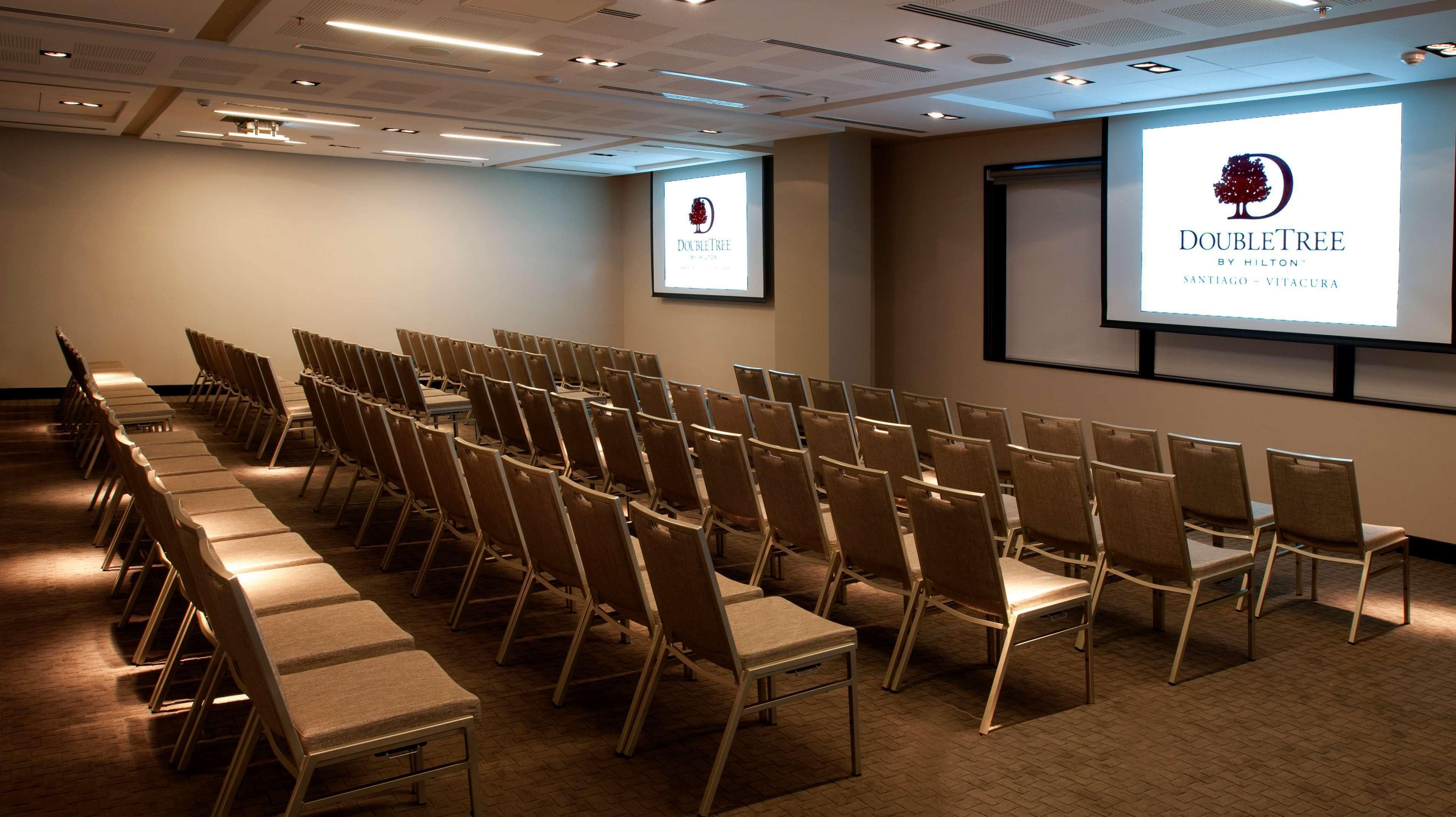 Un salón de conferencias con filas de sillas y una pantalla proyectora mostrando el logotipo de DoubleTree.