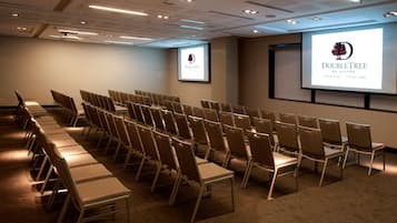 Un salón de conferencias con filas de sillas y una pantalla proyectora mostrando el logotipo de DoubleTree.