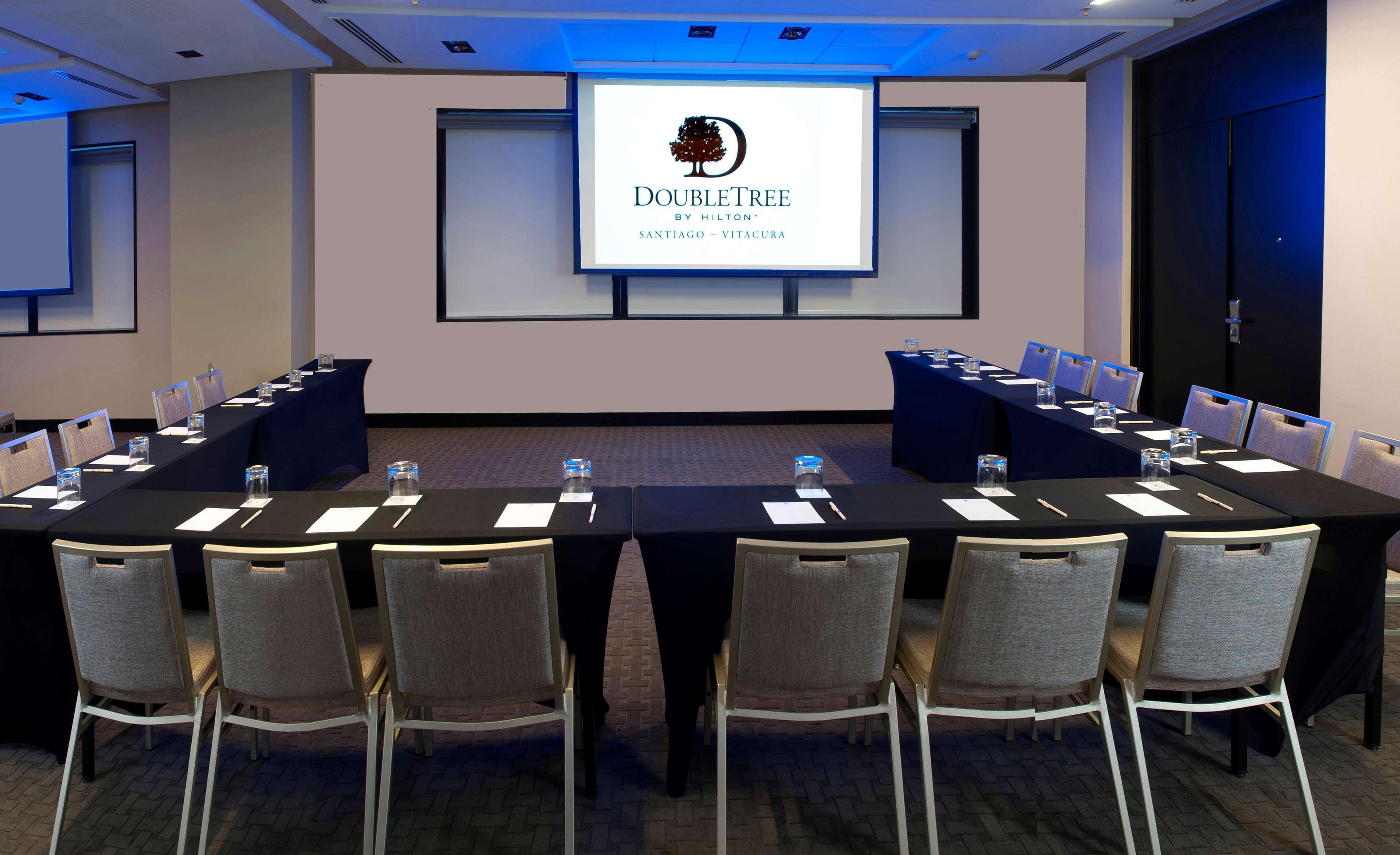 A conference room with a long table, chairs, and a screen displaying the DoubleTree logo.