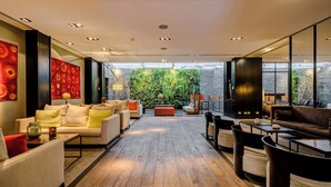 Amplia sala de estar con piso de madera, muebles modernos y un ventanal con vistas a un jardín.