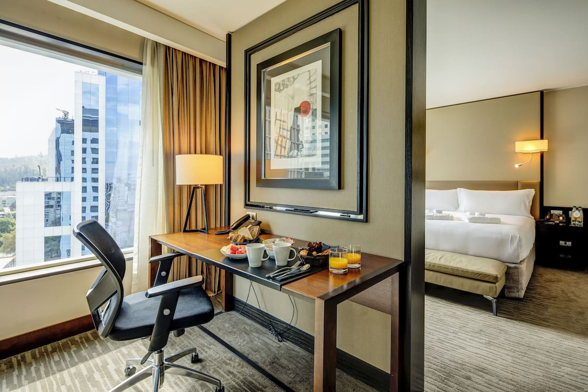 Ein Hotelzimmer mit Schreibtisch, Stuhl, Bett und einem gerahmten Bild an der Wand.