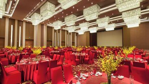 A banquet hall with round tables, red chairs, and chandeliers. - Holiday Inn Putian Xiuyu by IHG (Putian)