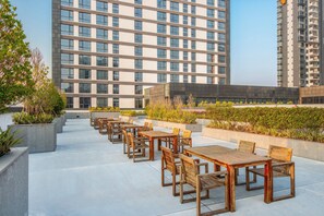 A rooftop terrace with outdoor seating and a view of a high-rise building. - Holiday Inn Putian Xiuyu by IHG (Putian)