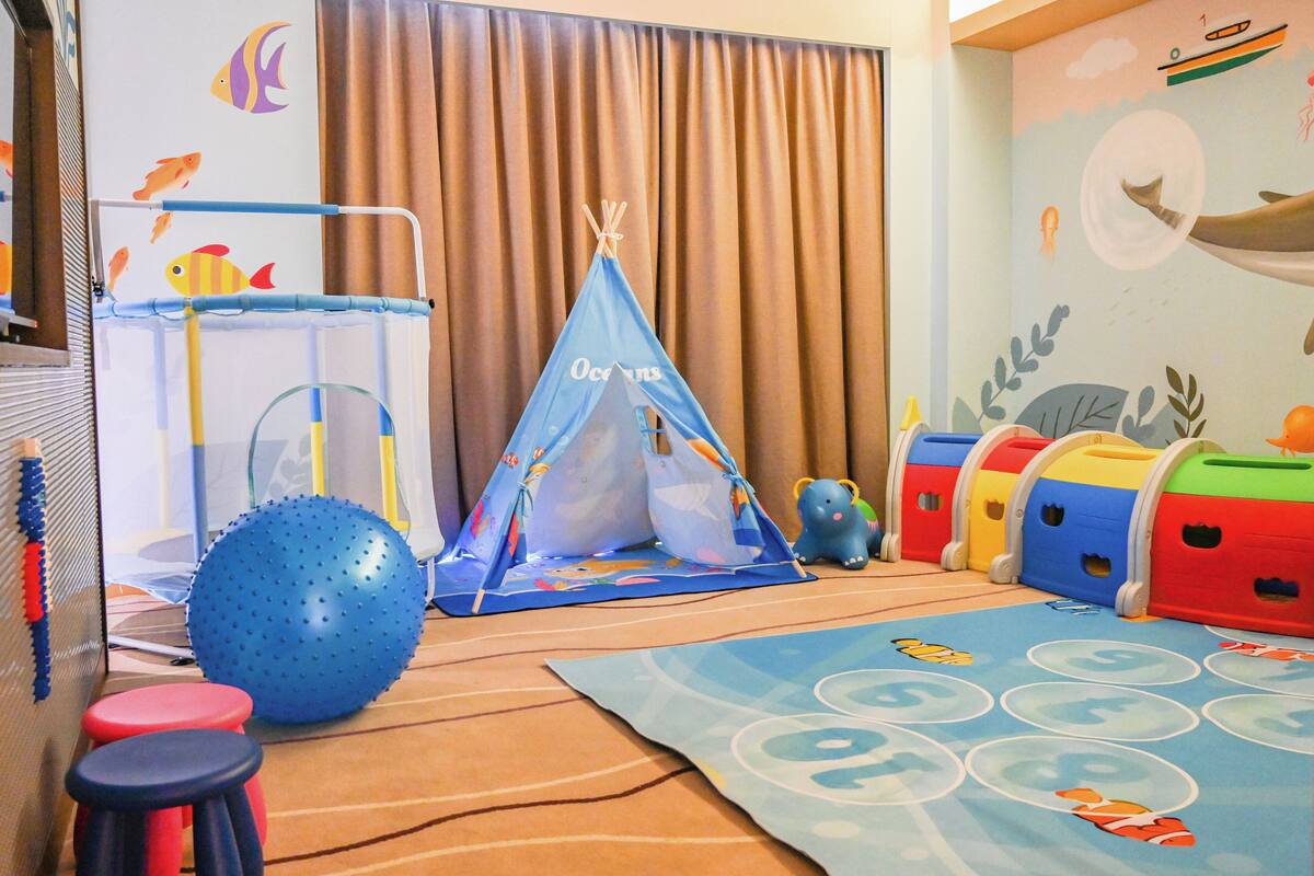 A play area with a blue ball, a teepee, and colorful storage bins.