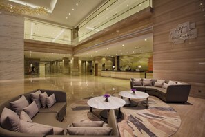 A spacious lobby with a high ceiling, marble flooring, a reception desk, and seating areas. - Holiday Inn Putian Xiuyu by IHG (Putian)