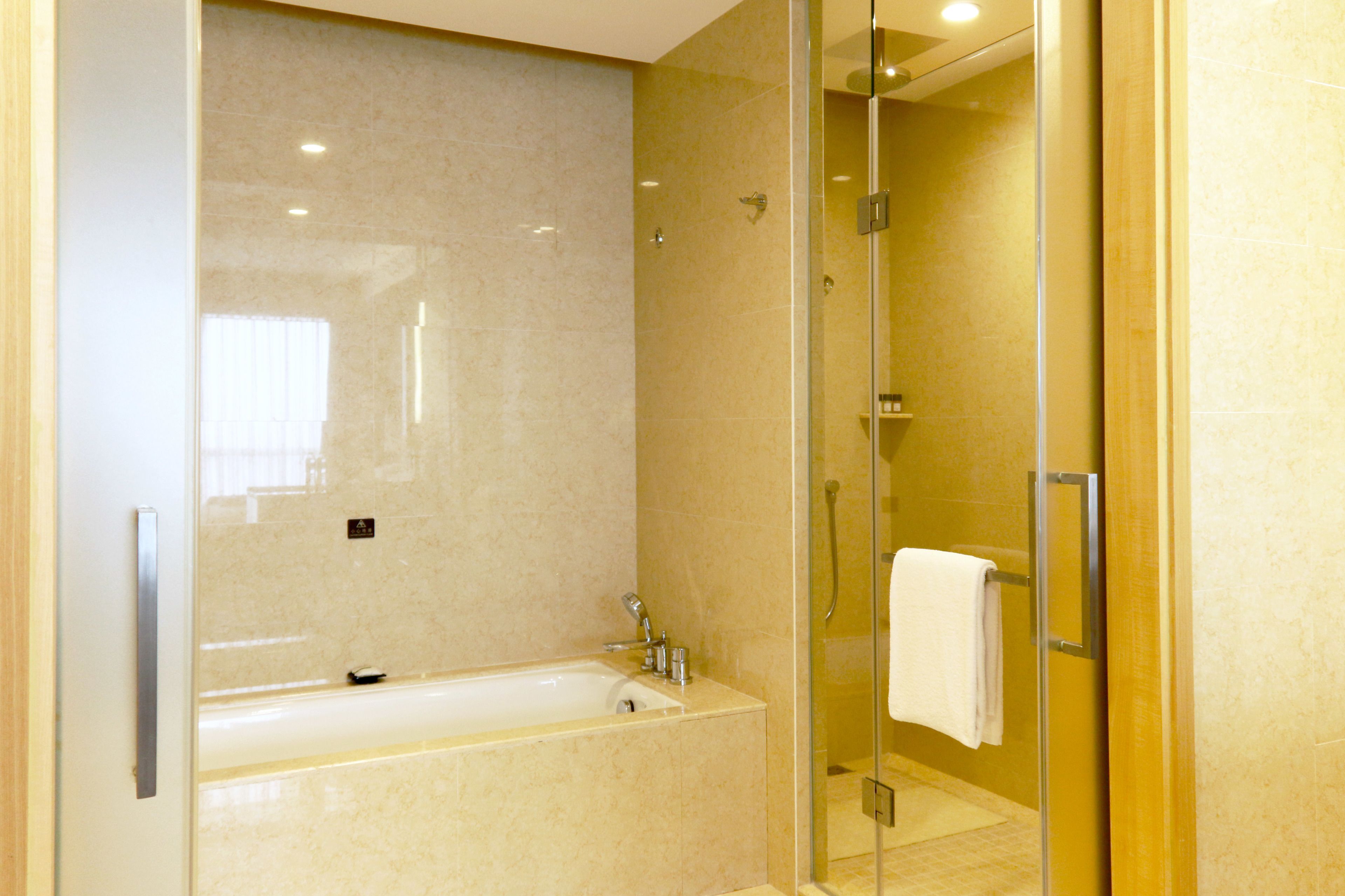 A modern bathroom with a glass-enclosed shower, a standalone bathtub, and a glass door.